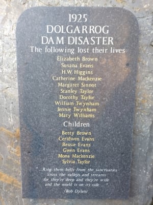 A dark stone memorial plaque mounted on a wall, engraved with a list of names.