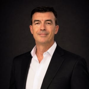 A profile photo of John Hammond against a dark background.