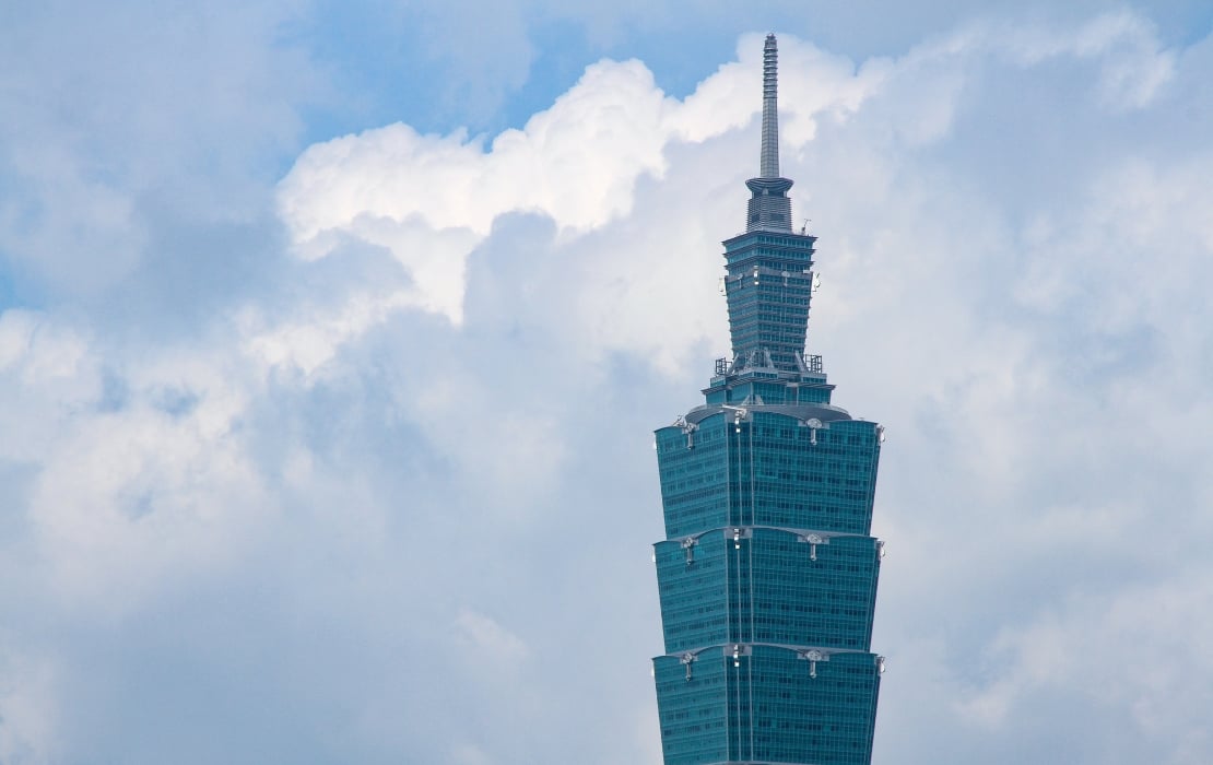 Close-up view of the upper section of Taipei 101 against a backdrop of bright, cloudy sky.