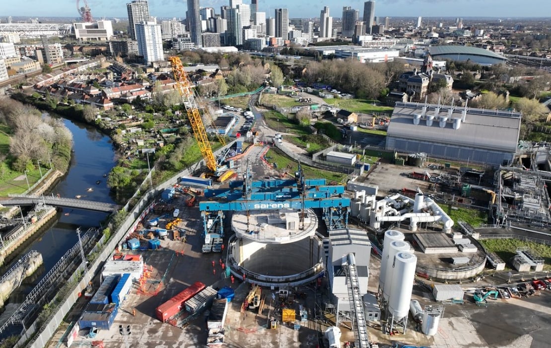 Aerial view of Thames Tideway Tunnel construction site in London featuring cranes, machinery, and surrounding urban landscape. Image by Thames Tideway.