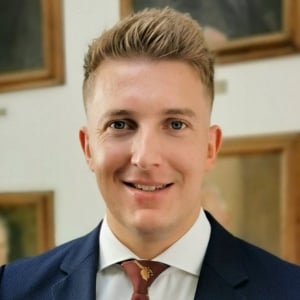 A profile photograph of Christopher Ackland wearing a navy suit.