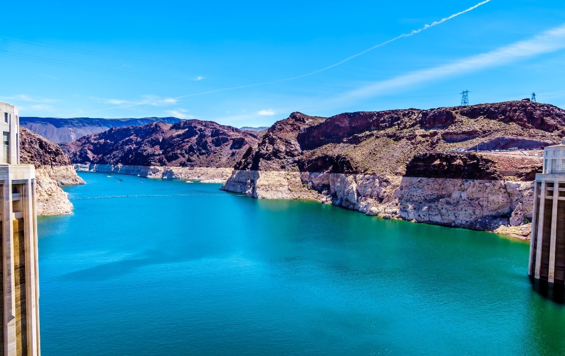 A photo of Lake Mead which is held by the Hoover Dam. The lake is at lower levels, and the water is bright teal.
