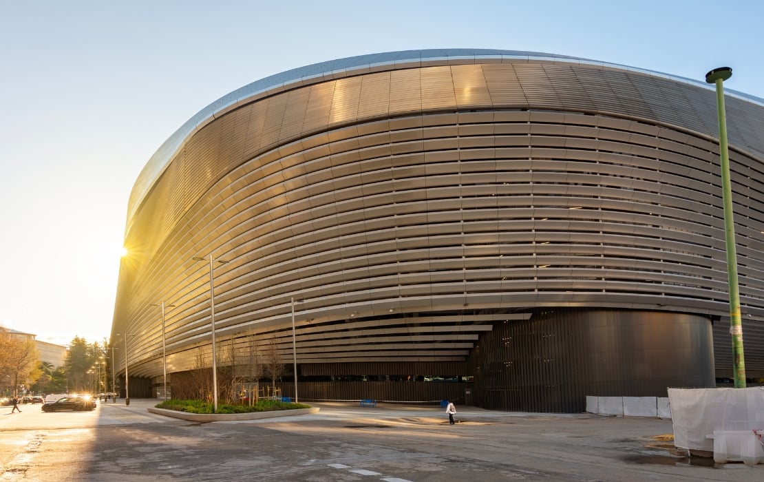 A photo of the exterior of the renovated Santiago Bernabéu Stadium in Madrid, Spain, featuring its new stainless steel facade.