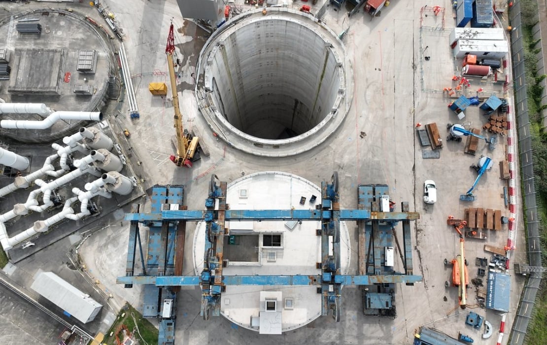 Aerial view of Thames Tideway Tunnel shaft construction site showing deep circular excavation, cranes, and heavy machinery.