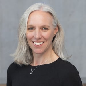 A headshot of Andrea Charlson against a grey background.